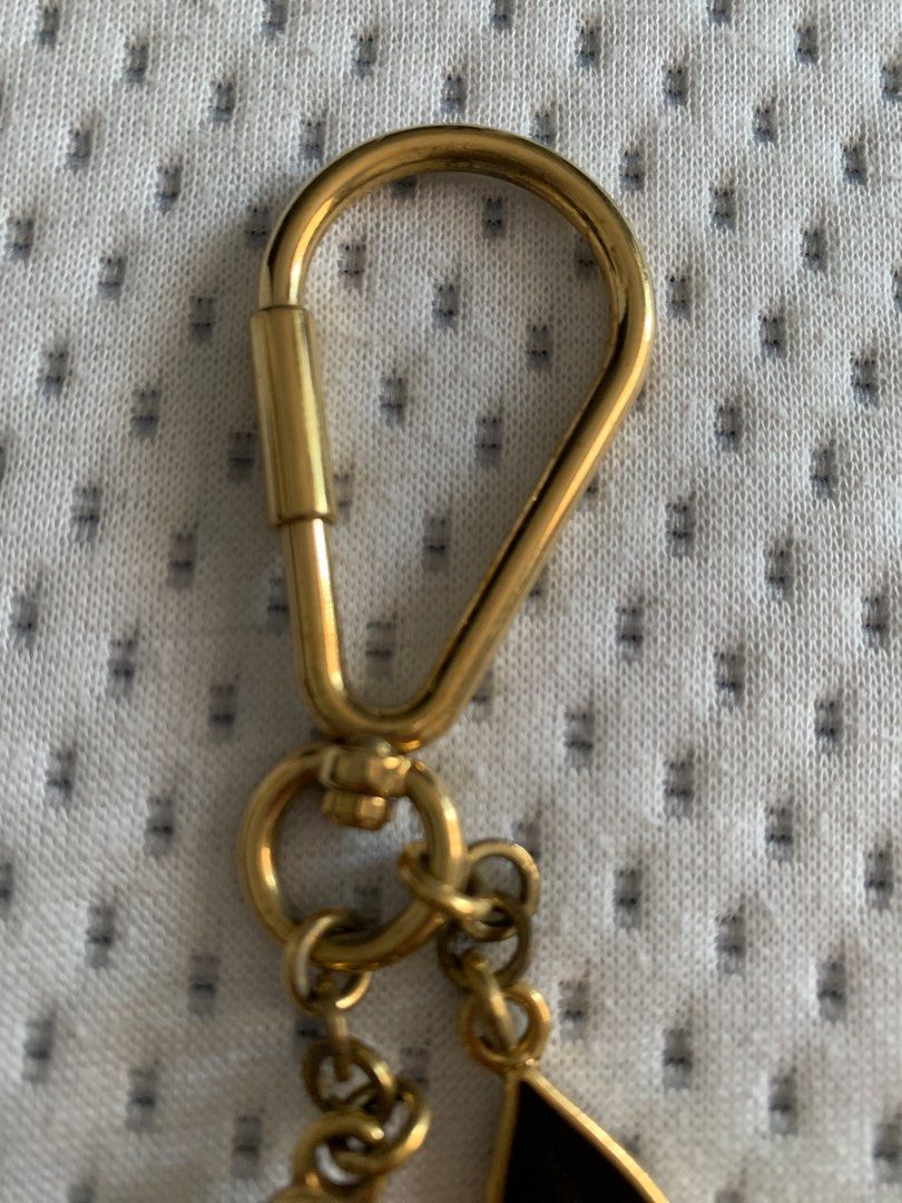 Louis Vuitton Key Chain (Category: Luxury Accessories) located in Rodriguez. Submitted by mbongscloset (Listing ID 1401548861, Image 3). Description: Louis Vuitton key chain features a gold-tone finish with two charms. One charm is a flower shape with the Louis Vuitton logo, and the other is the LV logo. The key chain has a clasp for easy attachment to bags or keys. A stylish accessory to add a touch of luxury..