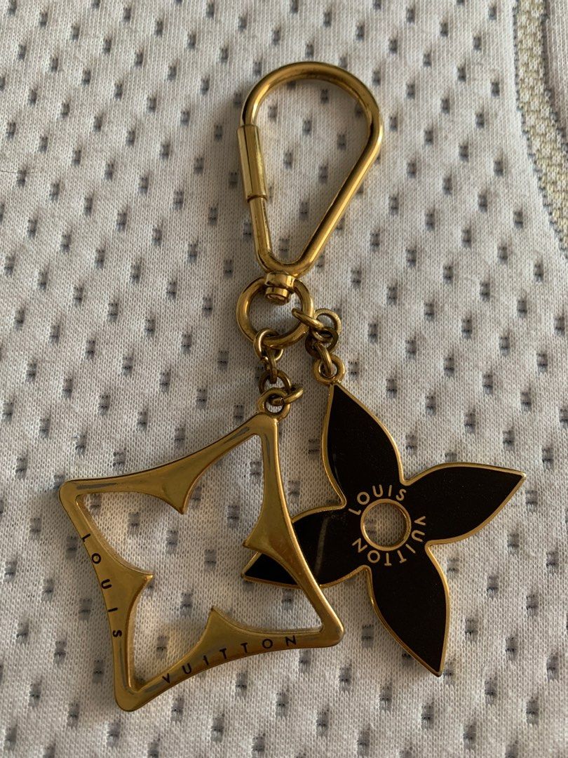 Louis Vuitton Key Chain (Category: Luxury Accessories) located in Rodriguez. Submitted by mbongscloset (Listing ID 1401548861, Image 1). Description: Louis Vuitton key chain features a gold-tone finish with two charms. One charm is a flower shape with the Louis Vuitton logo, and the other is the LV logo. The key chain has a clasp for easy attachment to bags or keys. A stylish accessory to add a touch of luxury..