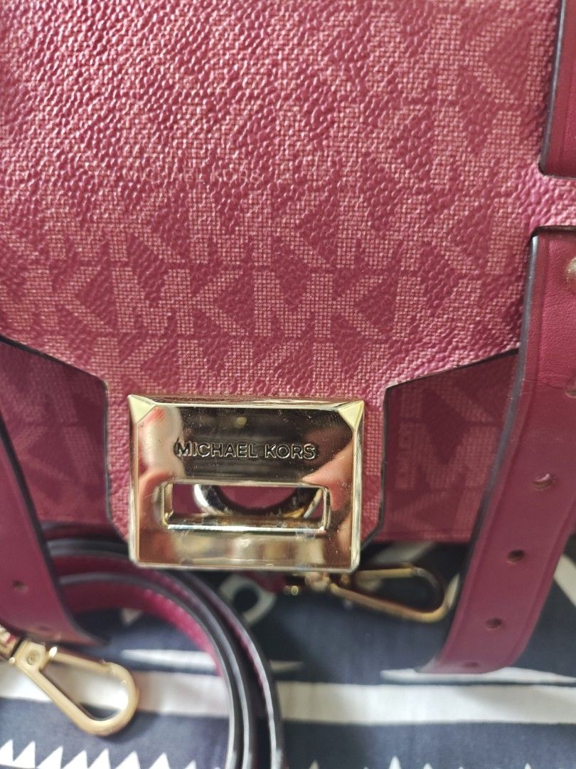 Michael Kors Handbag (Category: Luxury Bags & Wallets) located in Tabuk. Submitted by pinklarce (Listing ID 1401590807, Image 1). Description: - Authentic Michael Kors handbag - Color: Burgundy - Features the MK logo pattern - Gold-tone clasp with Michael Kors engraving - Includes a detachable strap - Made of a textured material -100 % Original.