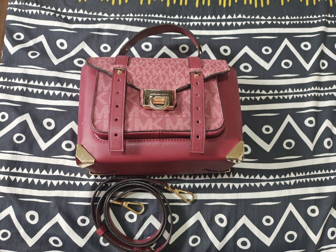 Michael Kors Handbag (Category: Luxury Bags & Wallets) located in Tabuk. Submitted by pinklarce (Listing ID 1401590807, Image 2). Description: - Authentic Michael Kors handbag - Color: Burgundy - Features the MK logo pattern - Gold-tone clasp with Michael Kors engraving - Includes a detachable strap - Made of a textured material -100 % Original.