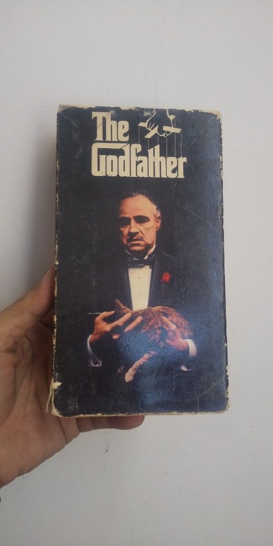 The Godfather VHS Tape (Category: Storybooks) located in Carmona. Submitted by rpute (Listing ID 1401606246, Image 1). Description: Godfather VHS tape. Features the movie title on the front and back of the case. The back of the case shows a wedding scene. The tape is labeled as -Fi. Produced by Paramount..
