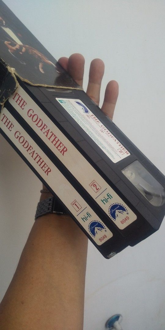 The Godfather VHS Tape (Category: Storybooks) located in Carmona. Submitted by rpute (Listing ID 1401606246, Image 3). Description: Godfather VHS tape. Features the movie title on the front and back of the case. The back of the case shows a wedding scene. The tape is labeled as -Fi. Produced by Paramount..