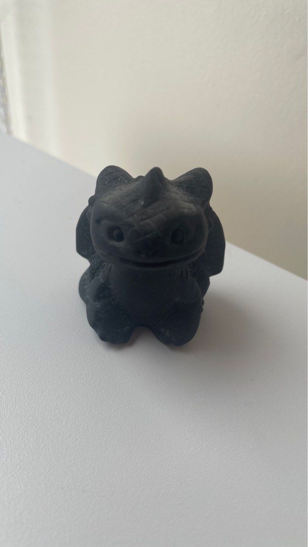 Toothless Dragon Figurine (Category: Figurines & Statues) located in General Trias. Submitted by jazzipotcollections (Listing ID 1401671193, Image 2). Description: - Black Toothless dragon figurine - Small and detailed sculpture - Features the character in a sitting position - Wings are slightly spread - Made of golden obsidian.