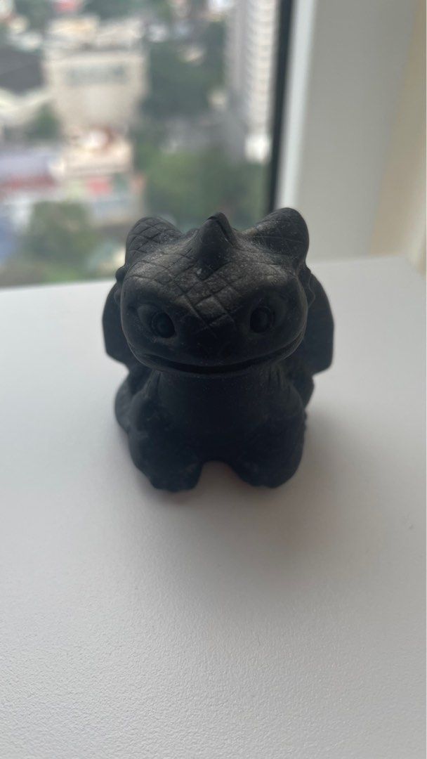 Toothless Dragon Figurine (Category: Figurines & Statues) located in General Trias. Submitted by jazzipotcollections (Listing ID 1401671193, Image 1). Description: - Black Toothless dragon figurine - Small and detailed sculpture - Features the character in a sitting position - Wings are slightly spread - Made of golden obsidian.