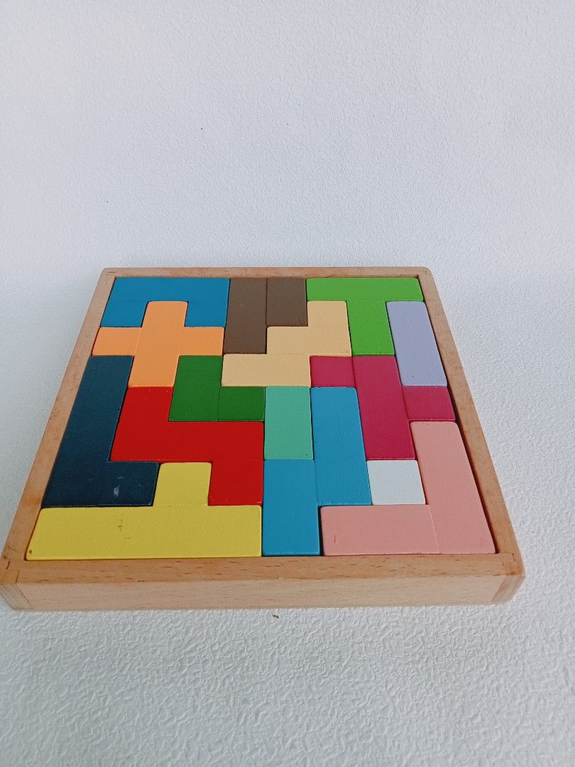 Wooden Tetris Puzzle (Category: Board Games & Puzzles) located in Rosario. Submitted by elysedeclutter (Listing ID 1401572392, Image 1). Description: Wooden Tetris puzzle with various colorful shapes. The puzzle pieces fit into a wooden frame. It's a great educational toy for kids to develop problem-solving skills and spatial reasoning. The puzzle is complete and ready to play..