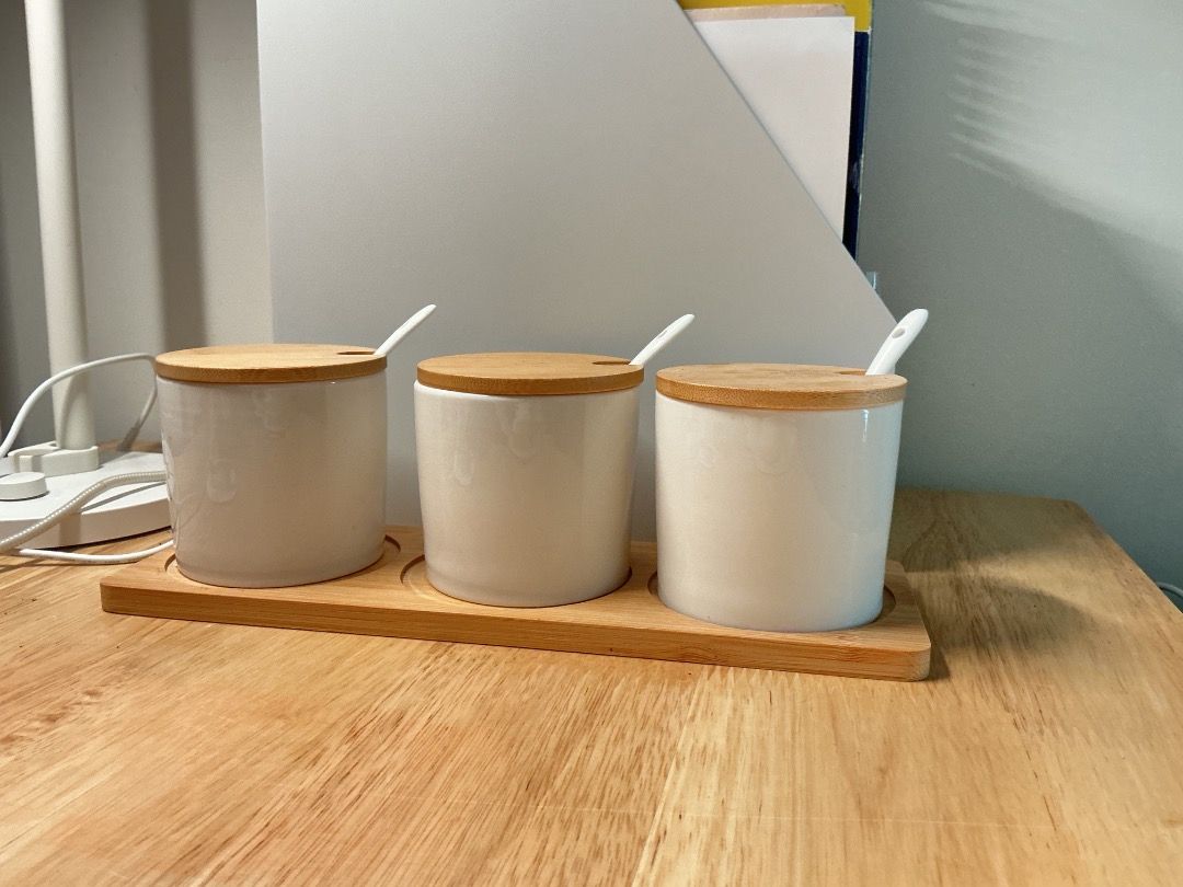 Ceramic Spice Jar Set with Wooden Lids (Category: Food Organization & Storage) located in Mandaluyong City. Submitted by keenfox-a0cb (Listing ID 1403292718, Image 2). Description: - Set includes three white ceramic spice jars. - Comes with wooden lids and small spoons. - Jars are cylindrical and clean. - Includes a wooden tray for organization. - Ideal for storing spices, herbs, or small ingredients. B.