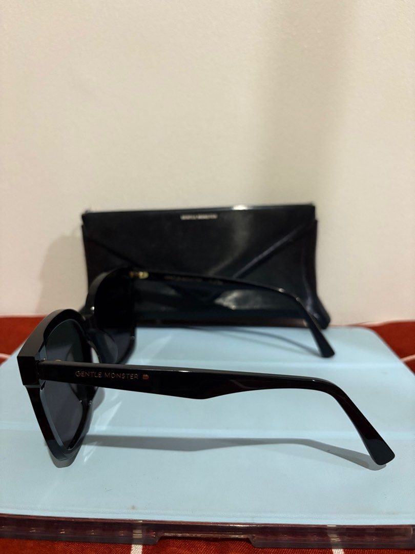 Gentle Monster HER 01 SUNGLASSES (Category: Sunglasses & Eyewear) located in Mandaluyong City. Submitted by bluezzzzz (Listing ID 1403341515, Image 2). Description: AE - Authentic Gentle Monster HER 01 sunglasses - Black frame with dark lenses - Includes box and cleaning cloth - Features a stylish, oversized design - Gentle Monster logo visible on case and paperwork - Perfect accessory.
