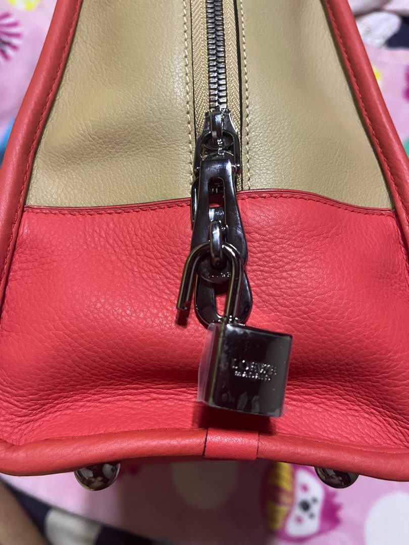 Loewe Amazona Handbag (Category: Luxury Bags & Wallets) located in Iloilo. Submitted by uapskie (Listing ID 1403393528, Image 3). Description: - Authentic Loewe Amazona handbag - Color: Beige and Red - Top handle design - Includes padlock with keys and dust bag - Secure zipper closure - Loewe logo visible - Protective metal feet at the bottom.