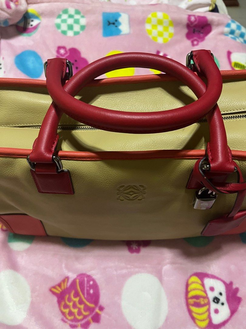 Loewe Amazona Handbag (Category: Luxury Bags & Wallets) located in Iloilo. Submitted by uapskie (Listing ID 1403393528, Image 1). Description: - Authentic Loewe Amazona handbag - Color: Beige and Red - Top handle design - Includes padlock with keys and dust bag - Secure zipper closure - Loewe logo visible - Protective metal feet at the bottom.