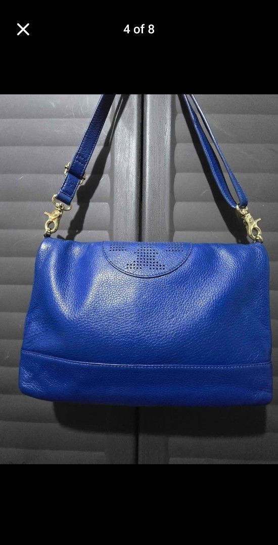 Tory Burch Blue Leather Handbag (Category: Luxury Bags & Wallets) located in Manila. Submitted by muliph (Listing ID 1403256547, Image 3). Description: Tory Burch handbag is a vibrant blue color. It features a detachable shoulder strap and gold-tone hardware. The interior has a light-colored lining with a small pocket. The bag has a flap closure with a magnetic snap. The exterior has a perforated logo detail..