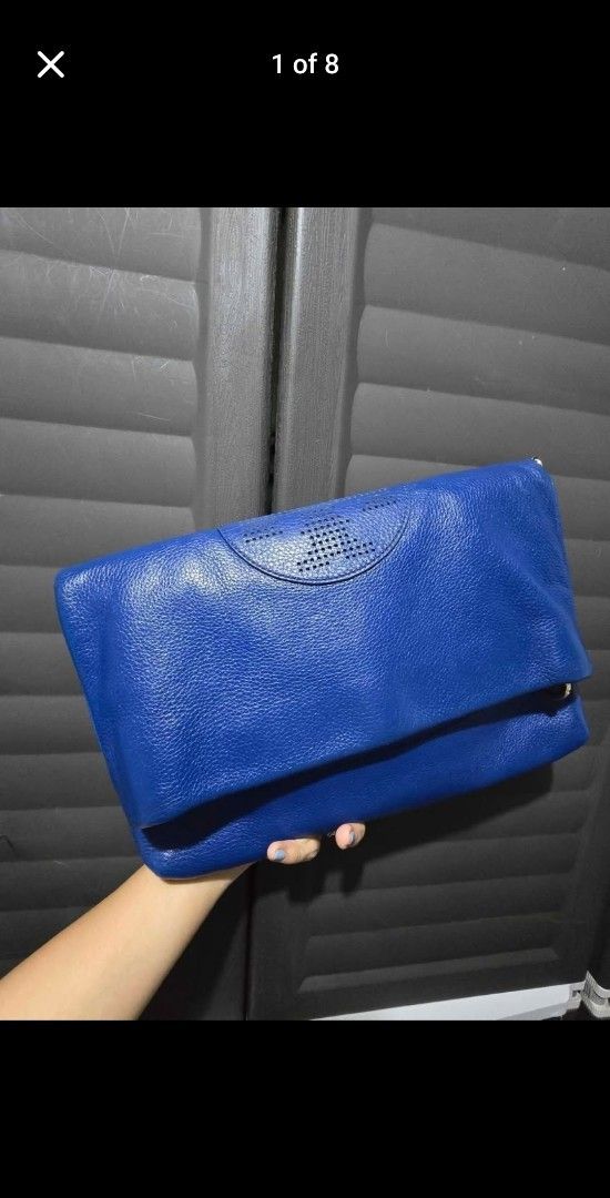 Tory Burch Blue Leather Handbag (Category: Luxury Bags & Wallets) located in Manila. Submitted by muliph (Listing ID 1403256547, Image 1). Description: Tory Burch handbag is a vibrant blue color. It features a detachable shoulder strap and gold-tone hardware. The interior has a light-colored lining with a small pocket. The bag has a flap closure with a magnetic snap. The exterior has a perforated logo detail..