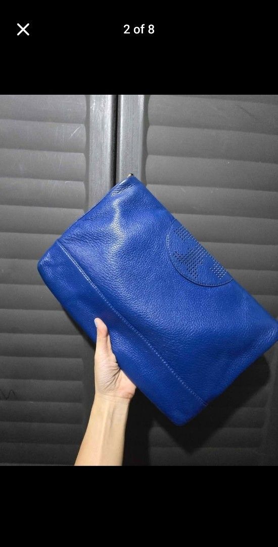 Tory Burch Blue Leather Handbag (Category: Luxury Bags & Wallets) located in Manila. Submitted by muliph (Listing ID 1403256547, Image 2). Description: Tory Burch handbag is a vibrant blue color. It features a detachable shoulder strap and gold-tone hardware. The interior has a light-colored lining with a small pocket. The bag has a flap closure with a magnetic snap. The exterior has a perforated logo detail..