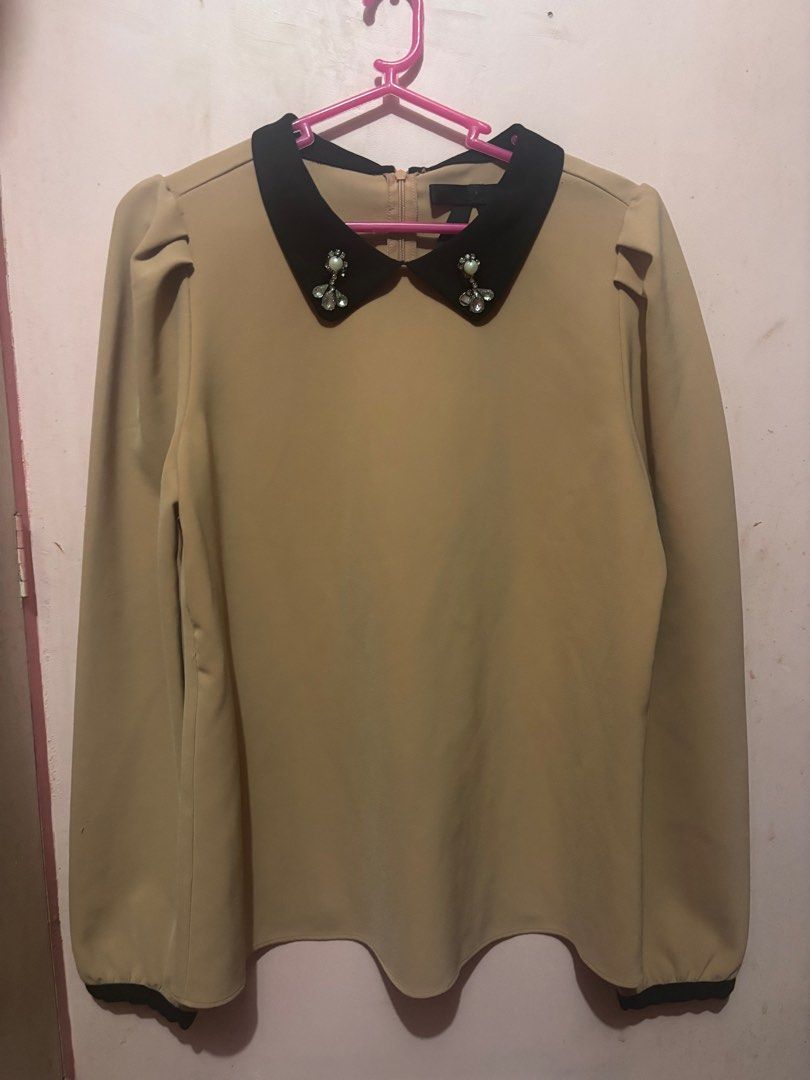 Beige Blouse with Black jeweled Collar (Category: Blouses) located in Pasig City. Submitted by kinderdrpt (Listing ID 1403558970, Image 1). Description: - Elegant beige blouse - Contrasting black collar with embellishments - Long sleeves with puff shoulders - Back zipper closure - Curved hemline - Black trim details - Suitable for various occasions.