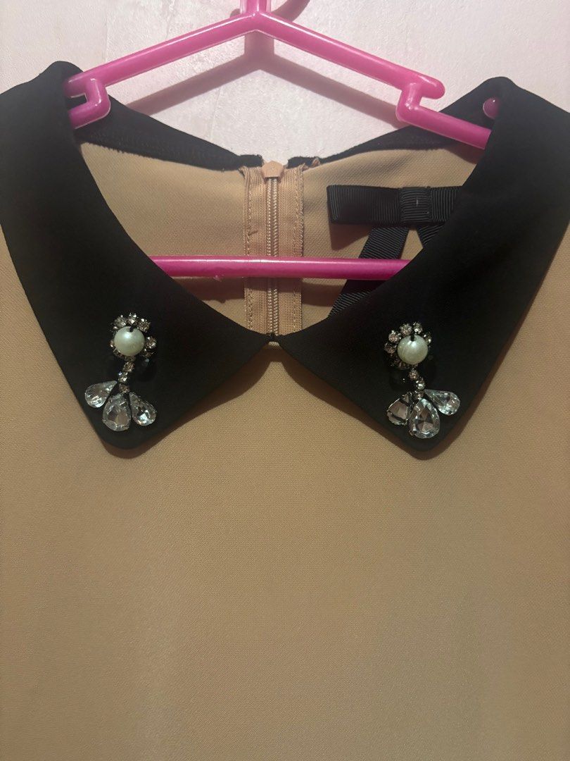 Beige Blouse with Black jeweled Collar (Category: Blouses) located in Pasig City. Submitted by kinderdrpt (Listing ID 1403558970, Image 2). Description: - Elegant beige blouse - Contrasting black collar with embellishments - Long sleeves with puff shoulders - Back zipper closure - Curved hemline - Black trim details - Suitable for various occasions.