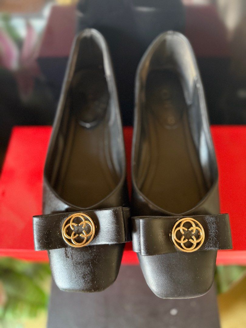 CLN Black School Shoes (Category: Flats & Sandals) located in Zamboanga. Submitted by iyodezamboanga (Listing ID 1403761598, Image 1). Description: Elegant black flats featuring a square toe design and a decorative bow with a gold-tone emblem. The flats appear to be made of a smooth material. They are a classic style suitable for various occasions. The shoes have a simple, yet sophisticated design..