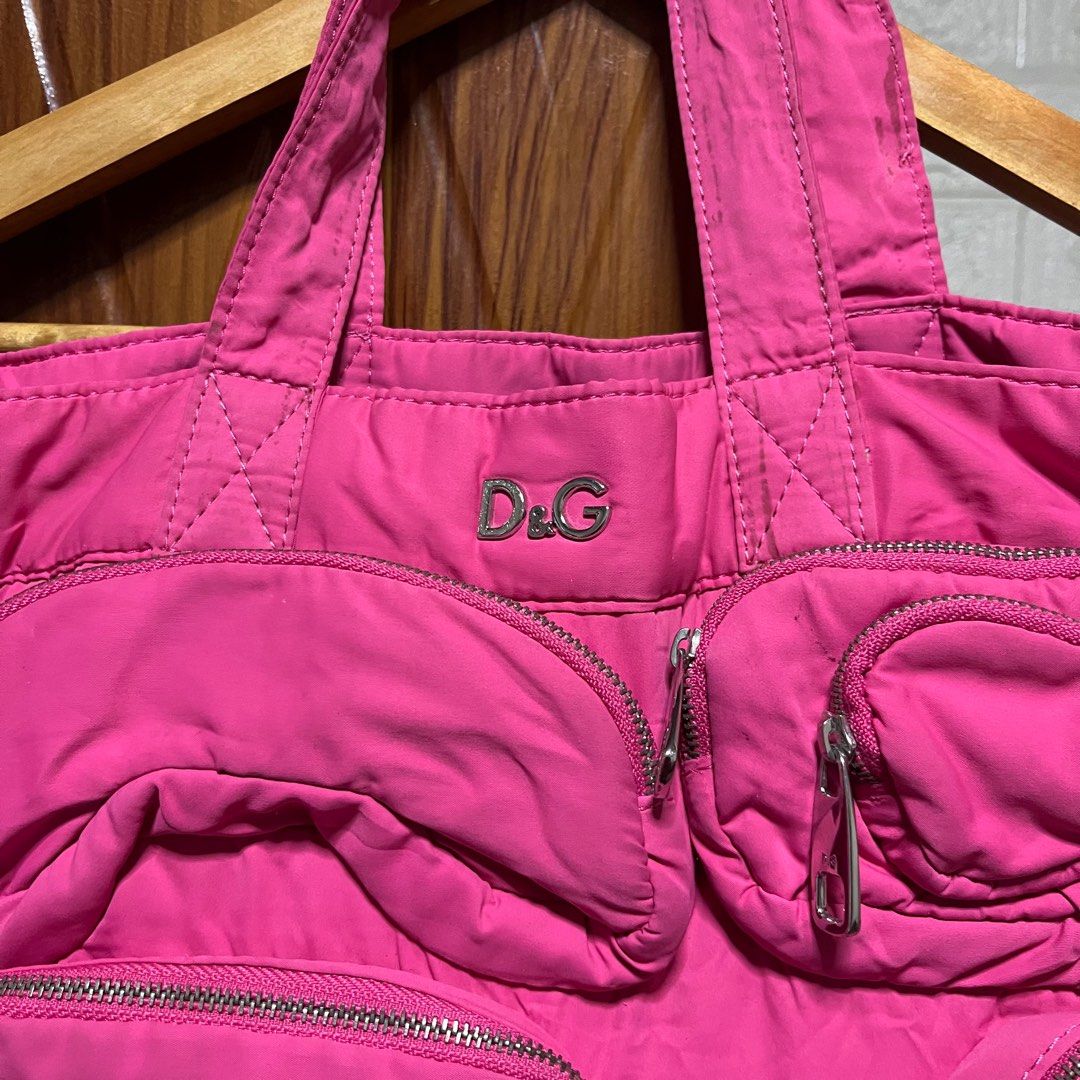 D&G Pink Tote Bag (Category: Luxury Bags & Wallets) located in Carmen. Submitted by rr_thrifts (Listing ID 1403623746, Image 3). Description: - D&G tote bag - Vibrant pink color - Multiple exterior pockets with silver zippers - D&G logo detail - Black interior - Interior zippered pocket - Includes "BAG LIZ" tag - Double handles.