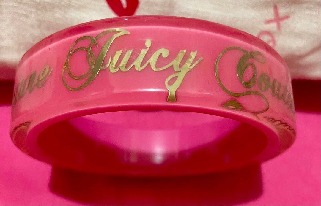Juicy Couture Pink Bracelet (Category: Bracelets) located in Quezon City. Submitted by stuffsrus (Listing ID 1403692668, Image 1). Description: Bracelet is a vibrant pink color. It features the words "Juicy Couture" in gold lettering around the band. It's a stylish accessory for any outfit..