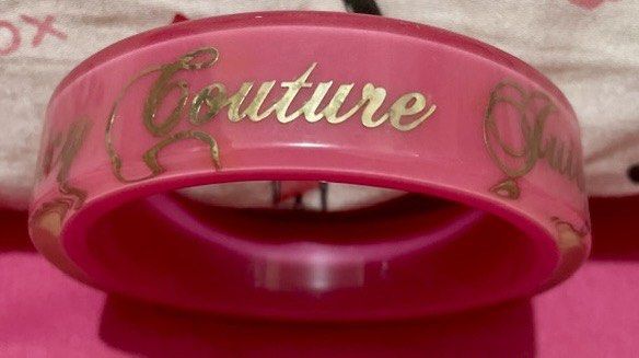 Juicy Couture Pink Bracelet (Category: Bracelets) located in Quezon City. Submitted by stuffsrus (Listing ID 1403692668, Image 3). Description: Bracelet is a vibrant pink color. It features the words "Juicy Couture" in gold lettering around the band. It's a stylish accessory for any outfit..