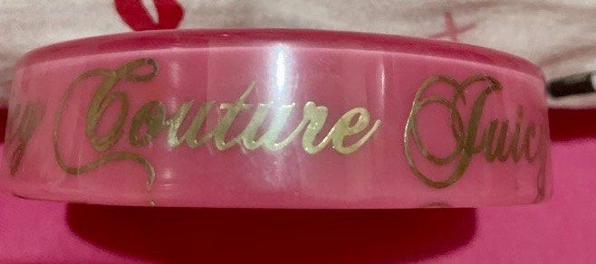 Juicy Couture Pink Bracelet (Category: Bracelets) located in Quezon City. Submitted by stuffsrus (Listing ID 1403692668, Image 2). Description: Bracelet is a vibrant pink color. It features the words "Juicy Couture" in gold lettering around the band. It's a stylish accessory for any outfit..