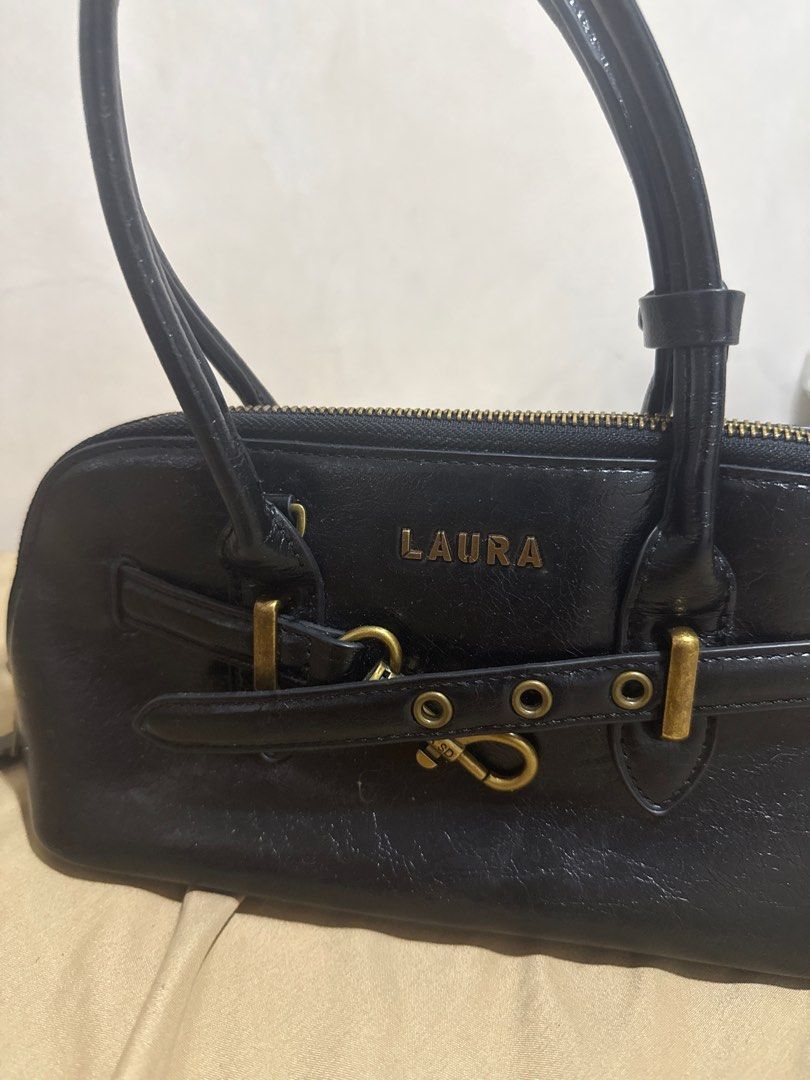 Laura & Shidai Black Handbag (Category: Purses & Pouches) located in Manila. Submitted by declutterwidme (Listing ID 1403822604, Image 2). Description: - Black handbag from Laura & Shidai - Top zipper closure - Two handles - Gold-colored clasp and hardware - Gray interior - Made in Seoul - Brand name "LAURA" on the front.