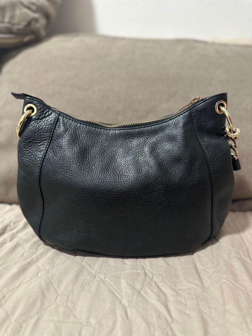 Michael Kors Black Leather Hobo Bag (Category: Luxury Bags & Wallets) located in Mandaluyong City. Submitted by grace.dt (Listing ID 1403836574, Image 2). Description: Black leather hobo bag from Michael Kors. Features a gold-tone chain strap and zipper details. Includes a tassel and the MK logo charm. The interior is lined with the Michael Kors logo. The bag has a zipper closure and a shoulder strap. The hardware is gold-toned..