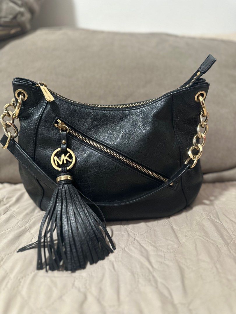 Michael Kors Black Leather Hobo Bag (Category: Luxury Bags & Wallets) located in Mandaluyong City. Submitted by grace.dt (Listing ID 1403836574, Image 1). Description: Black leather hobo bag from Michael Kors. Features a gold-tone chain strap and zipper details. Includes a tassel and the MK logo charm. The interior is lined with the Michael Kors logo. The bag has a zipper closure and a shoulder strap. The hardware is gold-toned..
