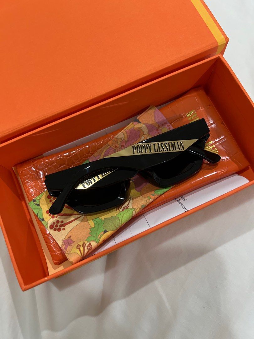 Poppy Lissiman Sunglasses (Category: Sunglasses & Eyewear) located in Bulacan. Submitted by __randomthings (Listing ID 1404032884, Image 2). Description: - Poppy Lissiman sunglasses - Black frame - Includes original box, case, and cleaning cloth - Unique frame shape - Brand name visible on temples - Perfect for fashion and sun protection.