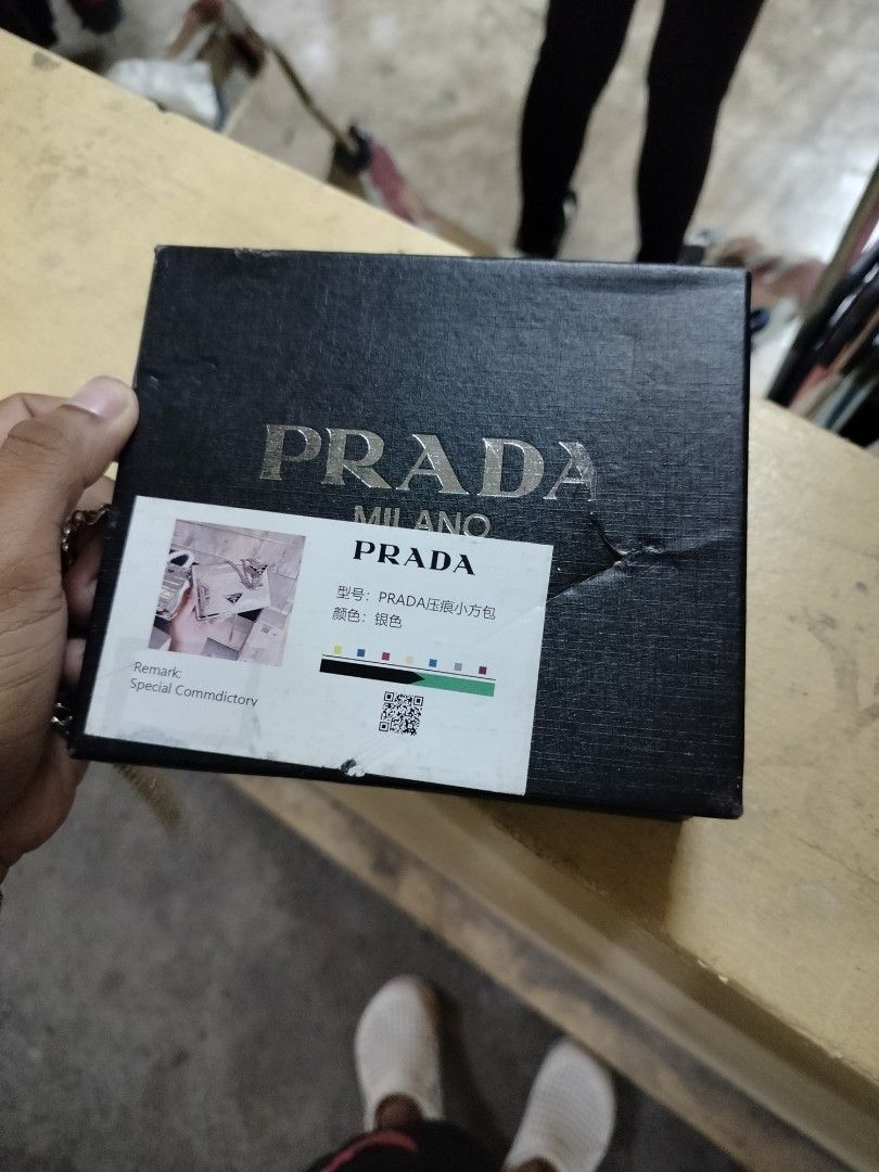 Prada Silver Wallet with Chain (Category: Luxury Bags & Wallets) located in Manila. Submitted by virgiliosa38485 (Listing ID 1404024284, Image 2). Description: - Prada wallet with a unique silver geometric design - Includes a matching chain - Comes with original box, dust bag, and authenticity card - Features a secure magnetic closure - Prada logo visible on front and inside - Includes a Prada keychain.