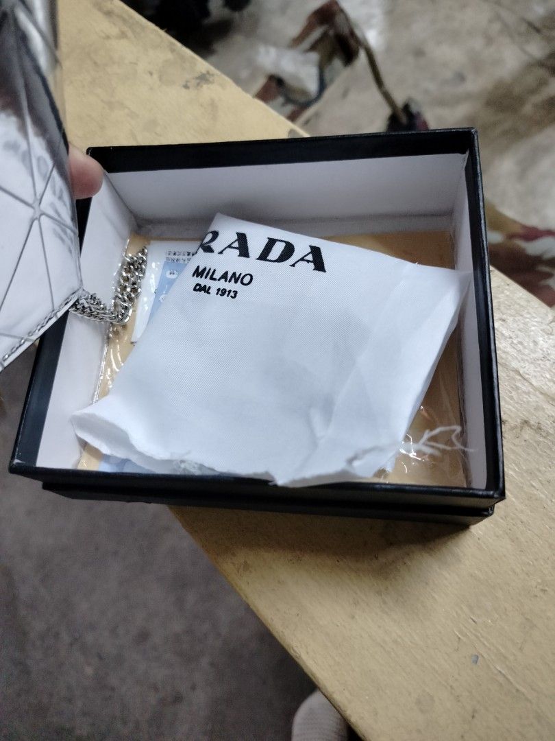 Prada Silver Wallet with Chain (Category: Luxury Bags & Wallets) located in Manila. Submitted by virgiliosa38485 (Listing ID 1404024284, Image 3). Description: - Prada wallet with a unique silver geometric design - Includes a matching chain - Comes with original box, dust bag, and authenticity card - Features a secure magnetic closure - Prada logo visible on front and inside - Includes a Prada keychain.