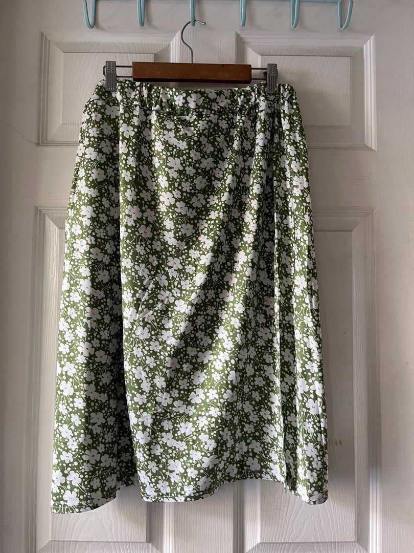 Floral Print Midi Skirt (Category: Skirts) located in Manila. Submitted by alexashops (Listing ID 1404239567, Image 1). Description: - Green midi skirt with white floral print - Elastic waistband - Side slit detail - Waist: Approximately 15 inches (unstretched) - Length: Approximately 27 inches - Lightweight and comfortable fabric.