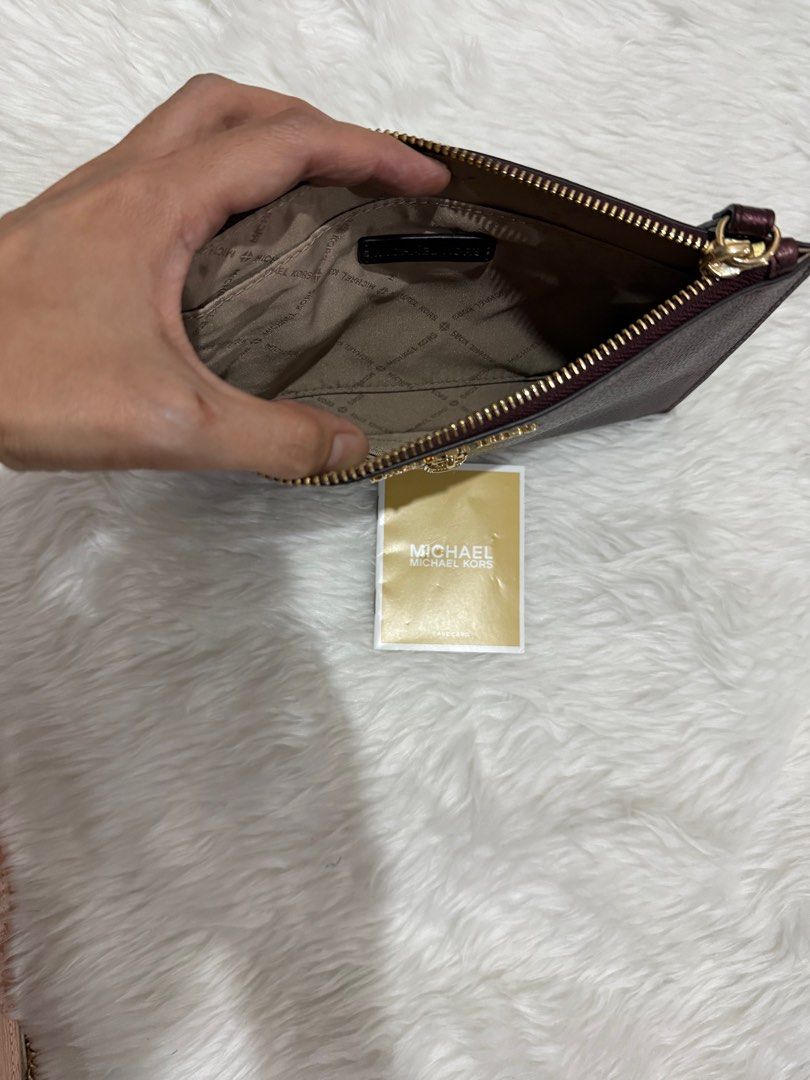 Michael Kors Clutch with Lock Detail (Category: Clutches) located in Makati City. Submitted by dj0108 (Listing ID 1404238101, Image 3). Description: Michael Kors clutch features a metallic burgundy exterior with a gold-tone lock detail. It has a wrist strap and a zippered closure. The interior is lined with a branded fabric. Includes a Michael Kors tag..