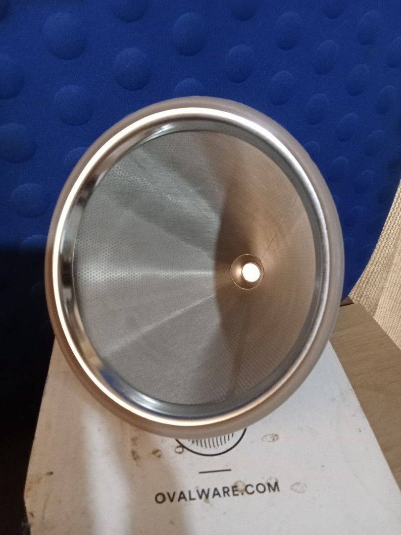 Ovalware RJ3 Stainless Steel Coffee Filter (Category: Coffee Machines & Makers) located in Bocaue. Submitted by marajapansurplus (Listing ID 1404209204, Image 2). Description: Ovalware RJ3 stainless steel coffee filter. It is a cone-shaped filter with a fine mesh design. The filter comes with its original box. The box features the Ovalware logo and product information. The filter is designed for brewing coffee and is made of stainless steel. Box 
