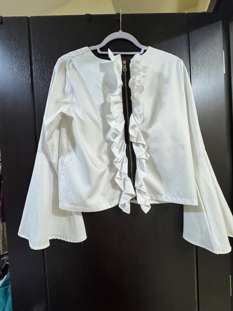 White Ruffle Front Blouse with Bell Sleeves (Category: Blouses) located in Manila. Submitted by elvbee (Listing ID 1404289432, Image 1). Description: Elegant white blouse featuring a ruffle front and stylish bell sleeves. It has a zipper closure and a round neckline. Can be worn 2 ways (zipper at the or at the front). This blouse is perfect for both casual and semi-formal occasions..