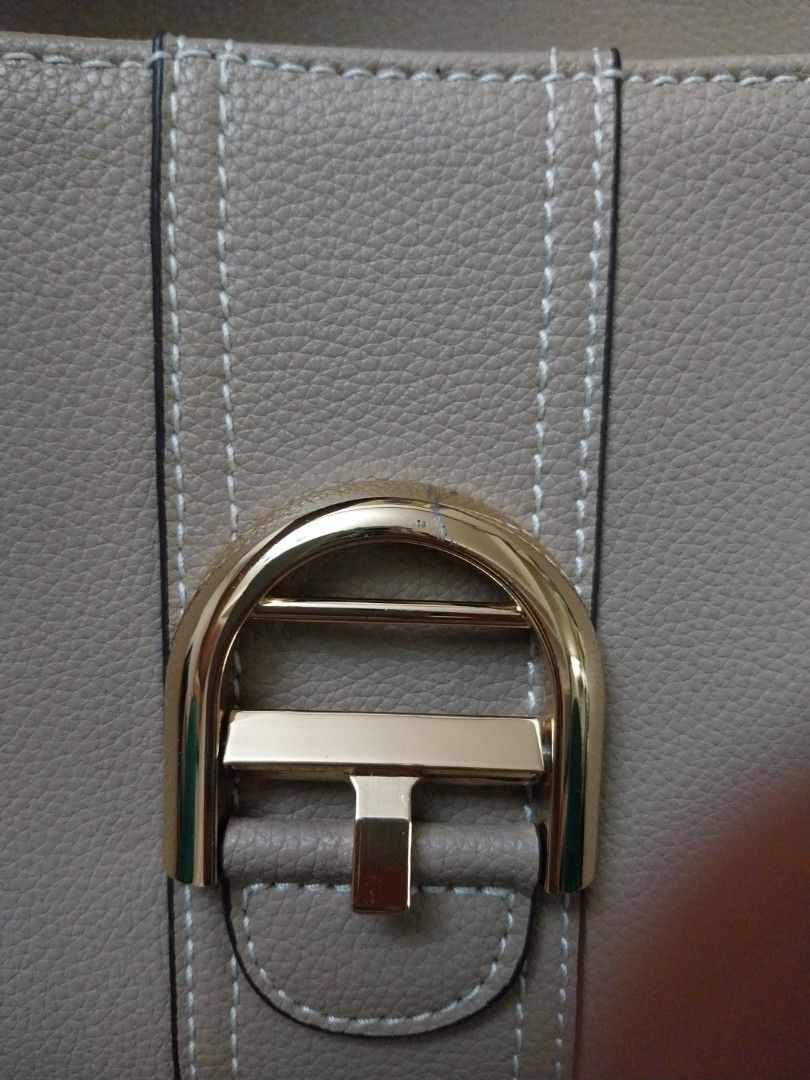 Grey Handbag with Gold Buckle (Category: Luxury Bags & Wallets) located in Mandaluyong City. Submitted by erlize (Listing ID 1404380308, Image 1). Description: Elegant grey handbag featuring a distinctive gold buckle. The bag has visible stitching details and a textured surface. The design includes a strap with a matching buckle. The overall aesthetic suggests a focus on both style and functionality. The bag's color and hardware create a sophisti