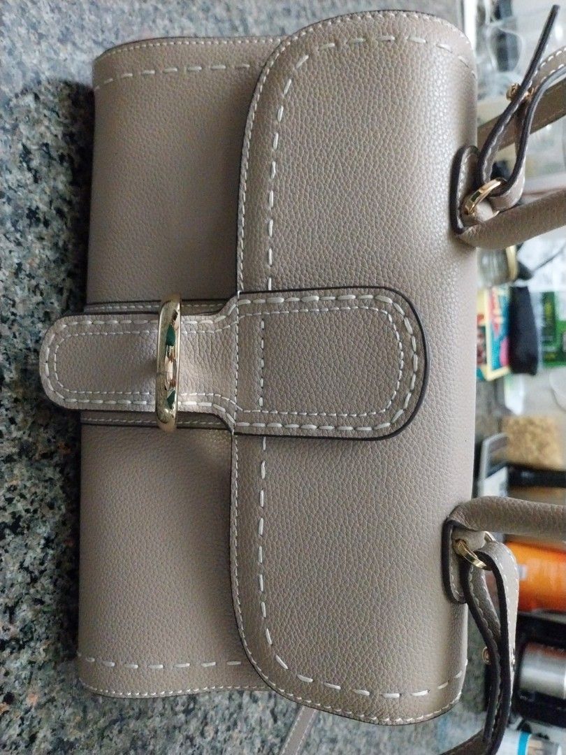 Grey Handbag with Gold Buckle (Category: Luxury Bags & Wallets) located in Mandaluyong City. Submitted by erlize (Listing ID 1404380308, Image 2). Description: Elegant grey handbag featuring a distinctive gold buckle. The bag has visible stitching details and a textured surface. The design includes a strap with a matching buckle. The overall aesthetic suggests a focus on both style and functionality. The bag's color and hardware create a sophisti