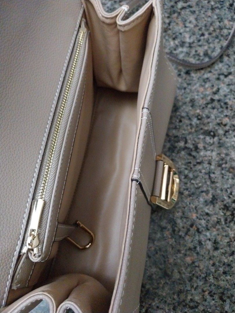 Grey Handbag with Gold Buckle (Category: Luxury Bags & Wallets) located in Mandaluyong City. Submitted by erlize (Listing ID 1404380308, Image 3). Description: Elegant grey handbag featuring a distinctive gold buckle. The bag has visible stitching details and a textured surface. The design includes a strap with a matching buckle. The overall aesthetic suggests a focus on both style and functionality. The bag's color and hardware create a sophisti