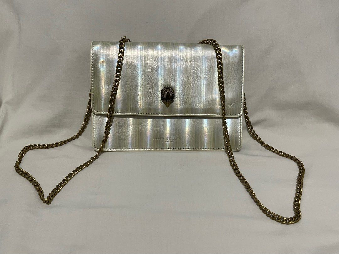 (Authentic) Kurt Geiger Shoreditch Silver Chain Bag (Category: Luxury Bags & Wallets) located in Manila. Submitted by hilligna (Listing ID 1404413723, Image 3). Description: Kurt Geiger Shoreditch bag features a silver exterior with a chain strap. The interior is gold with a zipper closure. The bag has a flap closure with a metal eagle head detail. The brand name is visible on the front and inside the bag. The bag has a rectangular shape..