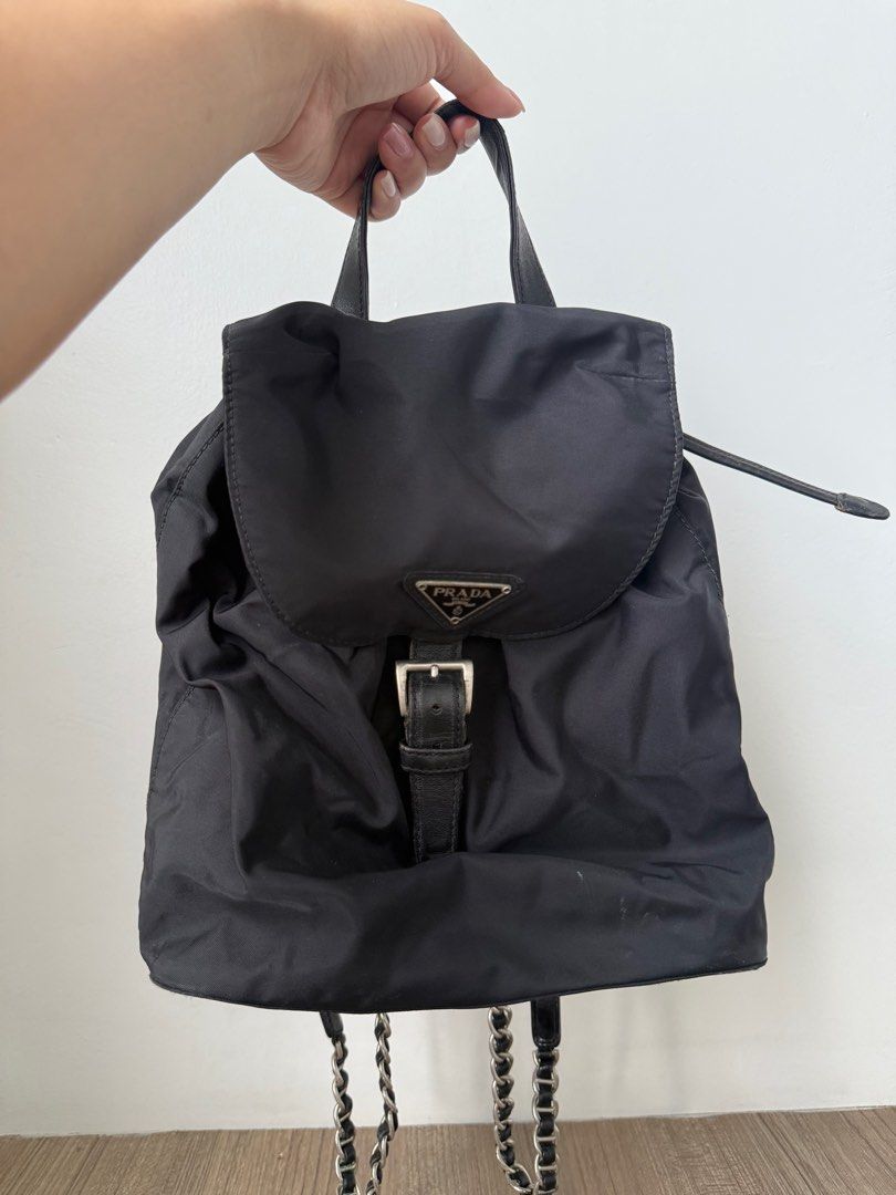Prada Black Nylon Backpack with Chain Straps (Category: Luxury Bags & Wallets) located in Iloilo. Submitted by imnolittlej (Listing ID 1404444629, Image 1). Description: - Authentic Prada backpack - Black nylon material - Chain straps (silver-toned) - Flap closure with buckle - Small Prada logo - Top handle and drawstring closure - Interior zipper.