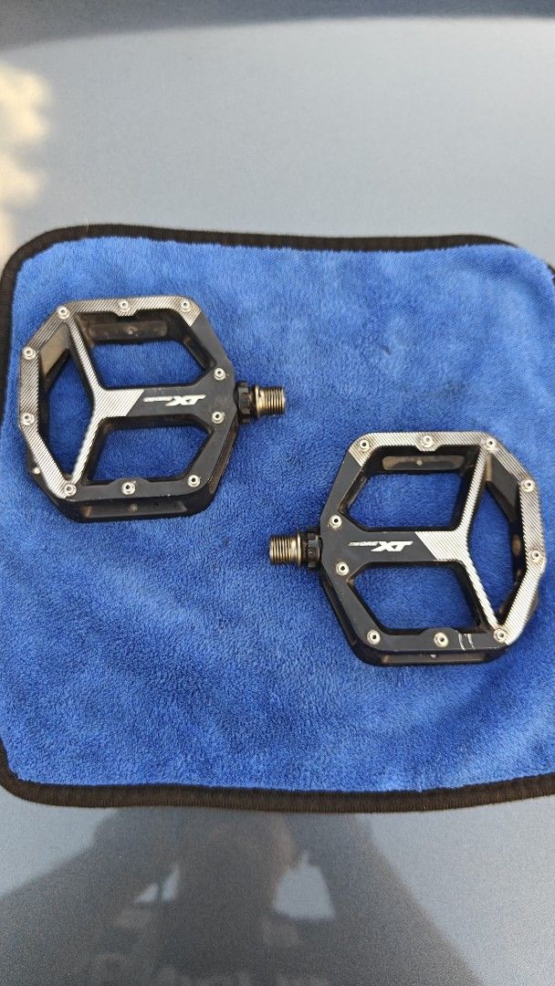 Shimano XT Pedals (Category: Bicycles) located in Calamba. Submitted by andreip05 (Listing ID 1404445915, Image 1). Description: - Shimano XT pedals - Black and silver color scheme - Platform style - Textured surface for enhanced grip - Visible spindle - Designed for mountain biking - Features the Shimano XT logo Seldom used,previously installed on a track bike. Bike is sold and selling these pedals separately. no issues, set and forget. XT legnd