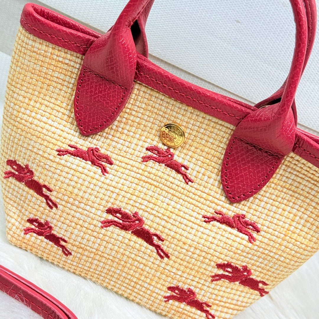 Micro Longchamp Paris Straw Tote Bag (Category: Luxury Bags & Wallets) located in Pasig City. Submitted by trendapparelph (Listing ID 1404738009, Image 2). Description: - micro Longchamp Paris Straw Tote Bag - Woven straw material - Red leather trim and handles - Embroidered with the iconic Longchamp horse logo - Includes a detachable strap.