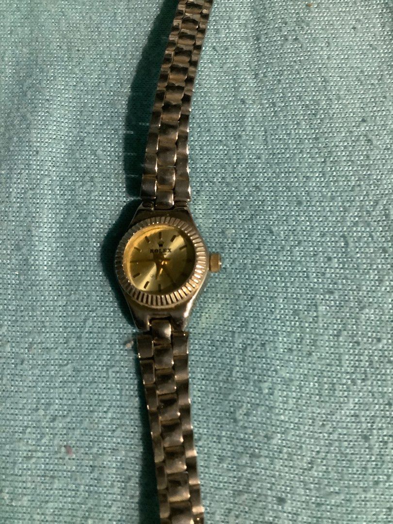 Rolex Quartz Watch (Category: Luxury Watches) located in Baguio. Submitted by agozun61 (Listing ID 1404687420, Image 3). Description: Watch features a gold-toned dial with the Rolex logo. It has a silver-toned metal strap and a fluted bezel. The back of the watch indicates it is Swiss made, water resistant, and uses a 11.60x3.10 battery. The watch has a small, round face and a crown on the side..