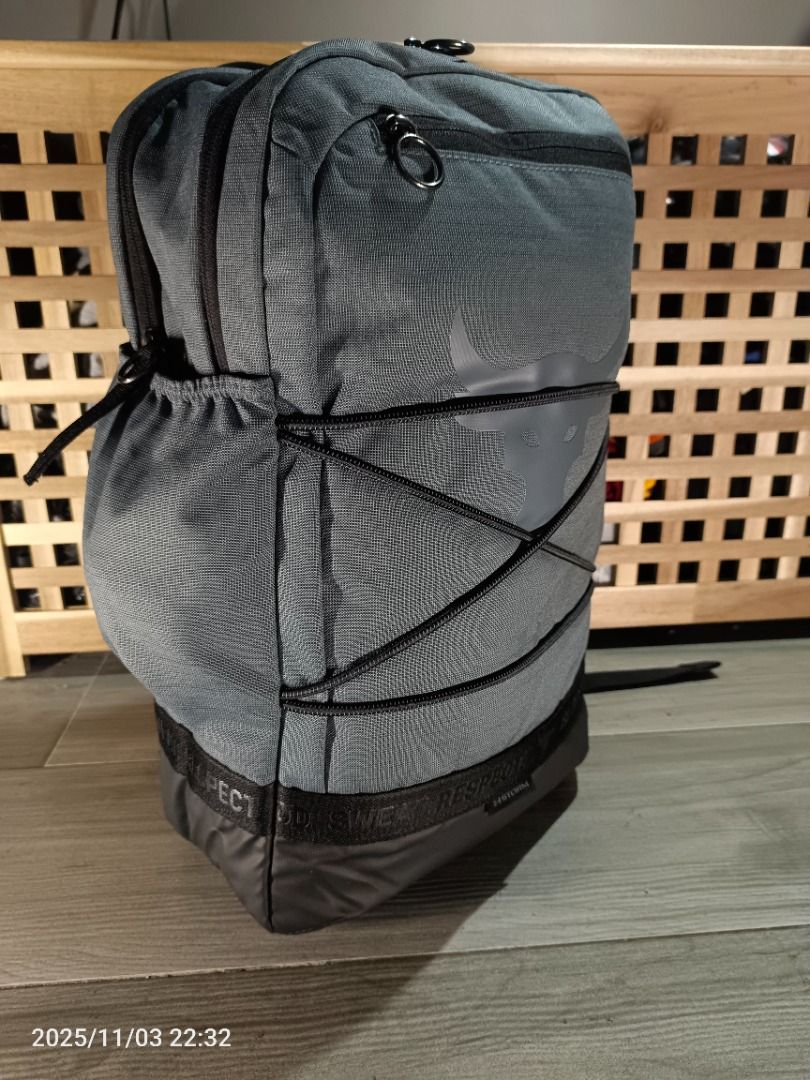 Under Armour Project Rock Brahma Backpack ( Gray ) (Category: Backpacks) located in Bacoor. Submitted by the.full.cart (Listing ID 1404723272, Image 3). Description: Under Armour Project Rock backpack features a gray color with the Project Rock logo. It has multiple compartments, including a front zippered pocket and side pockets. The backpack has adjustable straps and a top handle for easy carrying. The design includes black accents and the word