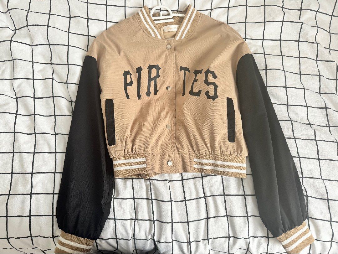 Varsity Jacket (Category: Coats, Jackets and Outerwear) located in Cyberjaya. Submitted by rhyu_ (Listing ID 1404604309, Image 1). Description: - Freesize, prefer S-small L - Black sleeves and beige body varsity jacket - Features "PIRATES" print on the front - Button-up closure - Striped detailing on collar and cuffs.