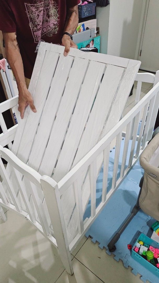 White foldable Wooden Baby Crib (Category: Cots & Cribs) located in Taguig. Submitted by dea_23 (Listing ID 1404671428, Image 3). Description: Used for 6 months, used only during daytime sa sala, baby has another one for naps and sleep sa room. Drop side, 2 levels With uratex foam with 1 free bed cover 24x40 inches Original price is around 3500 Flaw: -may dirt marks s side gawa ng kuya -chipped paint as seen on photos, natanggal nung ni remove un
