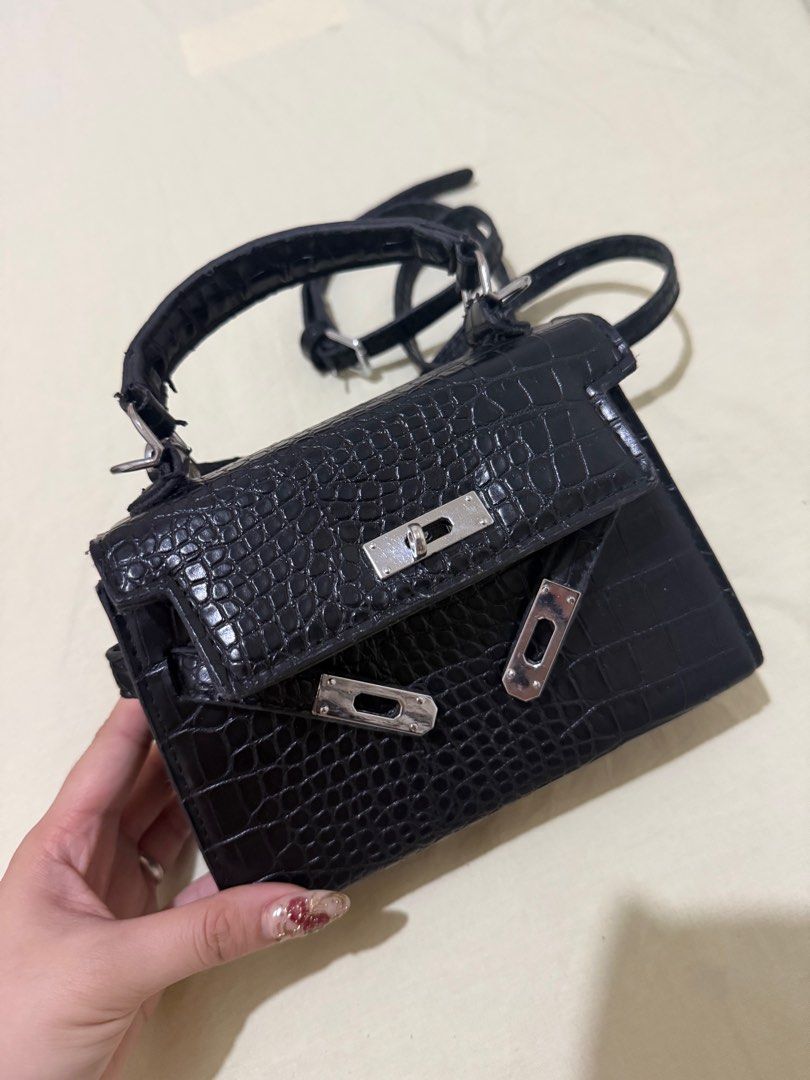 Hermes Kelly Mini Handbag (Category: Luxury Bags & Wallets) located in Angono. Submitted by xxxallaboutbagsxxx (Listing ID 1404934958, Image 1). Description: Black mini handbag with crocodile-embossed design. Features a top handle, detachable shoulder strap, and silver-tone hardware. Includes a small zippered pocket. Made of faux leather. Price negotiable.