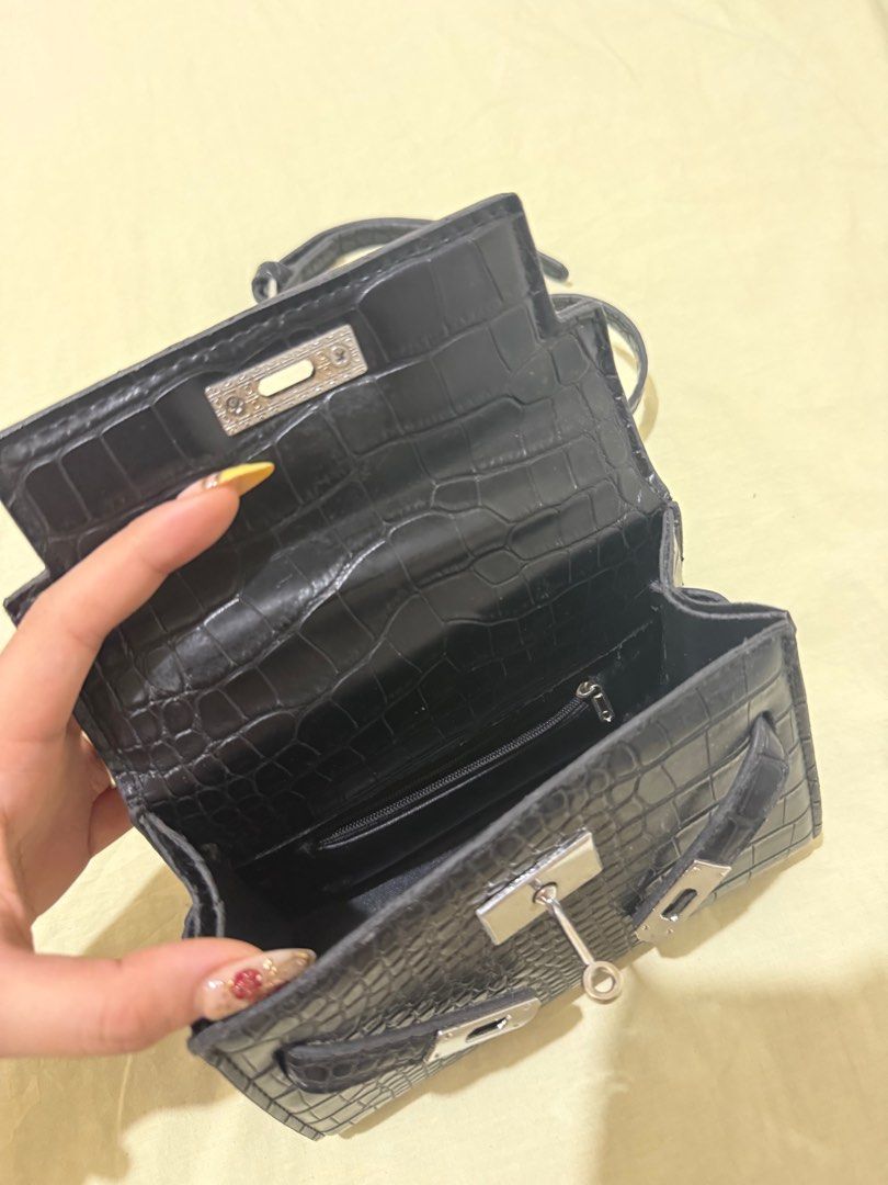 Hermes Kelly Mini Handbag (Category: Luxury Bags & Wallets) located in Angono. Submitted by xxxallaboutbagsxxx (Listing ID 1404934958, Image 2). Description: Black mini handbag with crocodile-embossed design. Features a top handle, detachable shoulder strap, and silver-tone hardware. Includes a small zippered pocket. Made of faux leather. Price negotiable.