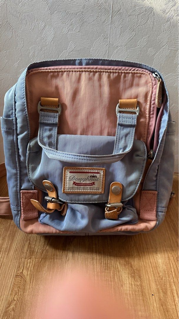 Doughnut Backpack （分類：背囊）位於 Hong Kong。 由 aau209 提交（商品編號 1404774708，圖片 1）。簡介： Authentic Doughnut backpack features a combination of blue and pink colours. It has a front flap with buckle closures and a top handle. The backpack has side pockets and adjustable shoulder straps. The brand's logo is visible on the front. 新舊見圖，尖沙咀／金鐘／炮台山地鐵站交收。