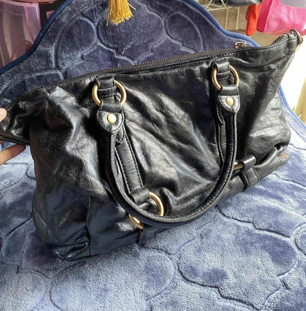 Miu Miu Black Leather Handbag (Category: Luxury Bags & Wallets) located in Taguig. Submitted by jerafelsan87737 (Listing ID 1404955230, Image 2). Description: - Authentic Miu Miu handbag - Black leather with gold-tone hardware - Double top handles - Secure zip closure - Spacious interior - Visible Miu Miu logo - Minor signs of wear.