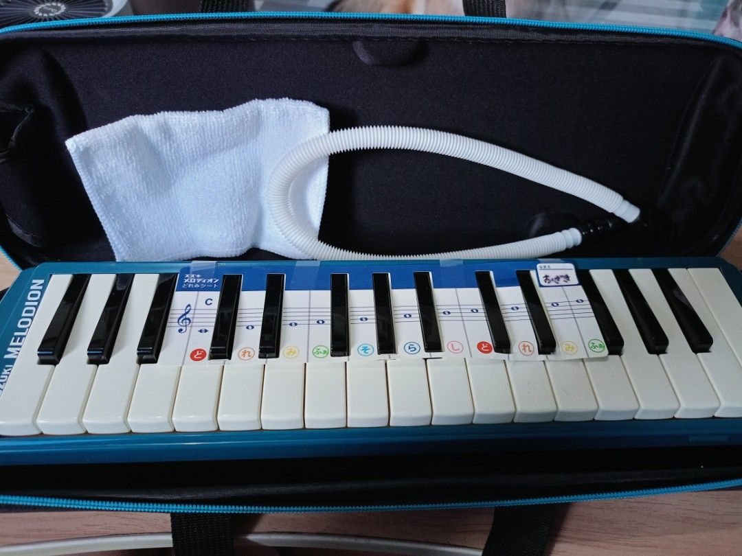 Suzuki Melodion (Category: Musical Instruments) located in Batangas. Submitted by ems10. (Listing ID 1404788539, Image 1). Description: Suzuki Melodion with carrying case and mouthpiece. The instrument has a blue body with white keys. Includes a cleaning cloth. The case is blue with a handle. The melodion has a sticker with musical notes and Japanese characters. The instrument measures approximately 40cm in length..