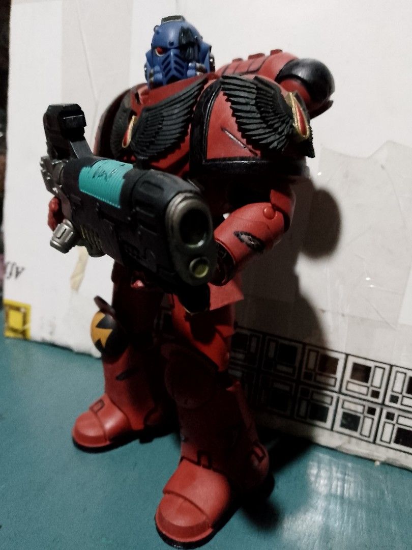 Warhammer 40k Space Marine Action Figure (Category: Action & Battle Toys) located in Taguig. Submitted by titus40k (Listing ID 1404838220, Image 1). Description: - Warhammer 40k Space Marine action figure - Features red armor - Includes black wing details - Blue helmet - Equipped with a large weapon with a green accent - Figure is posed on a surface - Background includes a box blood angels hellblaster mcfarlane 7inch figure good condition pick up